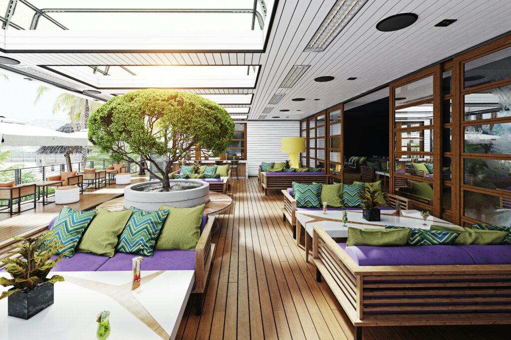 A modern cruise ship lounge with wood flooring, colorful seating, and lush greenery, offering a stylish and relaxing space for passengers