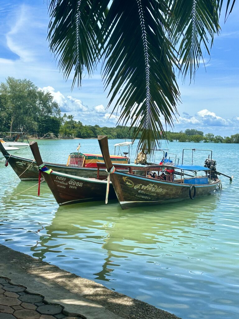 Traditional Thai longtail boats anchored in clear turquoise water off the coast of Koh Lanta, Thailand.