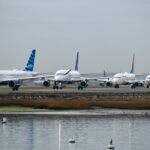 Commercial airplanes lined up on a runway during flight delays, symbolizing FAA air traffic disruptions and travel slowdowns.