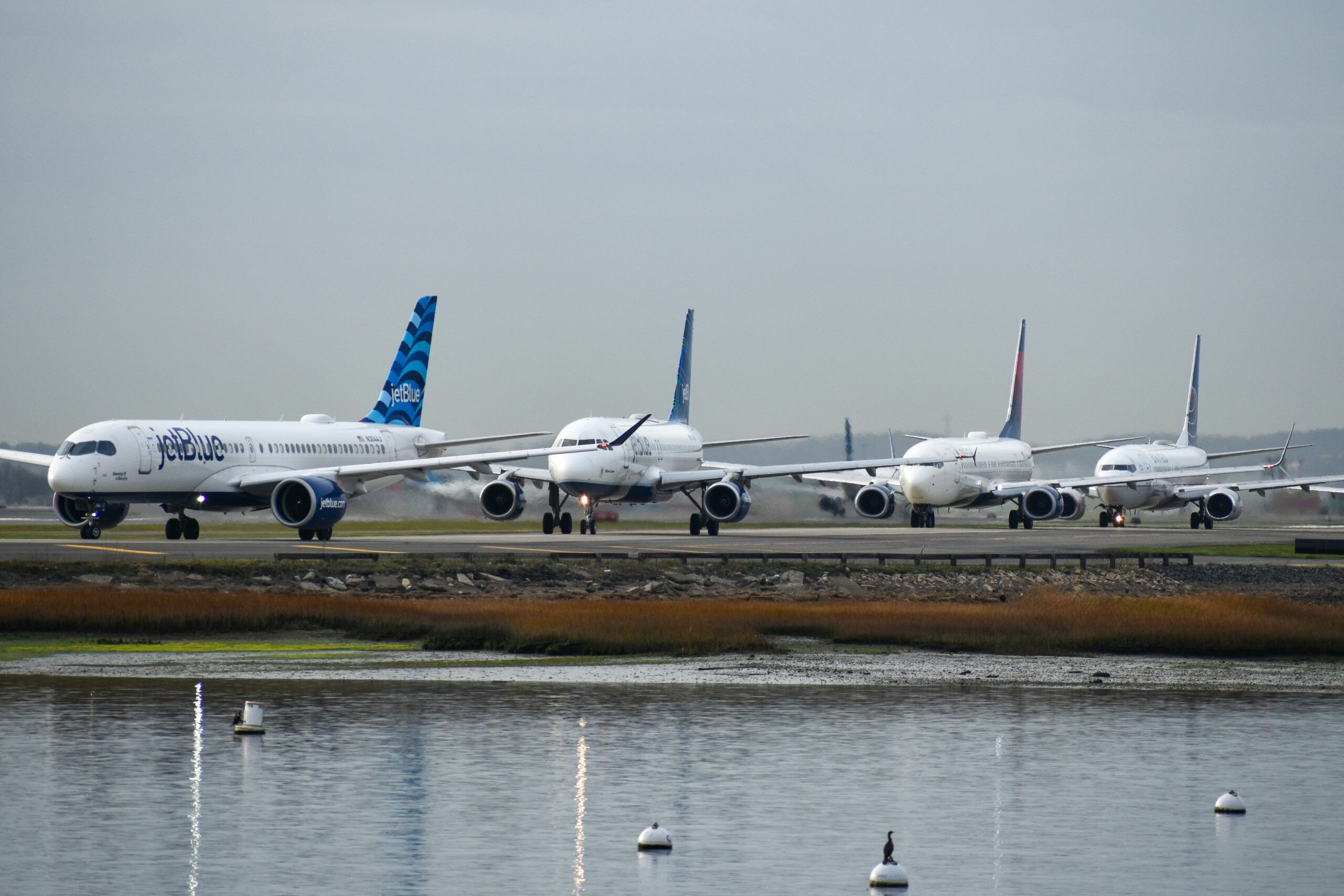 Commercial airplanes lined up on a runway during flight delays, symbolizing FAA air traffic disruptions and travel slowdowns.