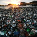 Sunrise over scattered sea glass on the beach, symbolizing transformation, patience, and growth through time.